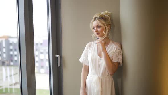 Beautiful Young Bride Looks Out of Window During Getting Ready