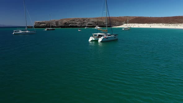 Boats Adrift Off The White Sand Shoreline Of Playa Balandra In La Paz, Mexico. panning right