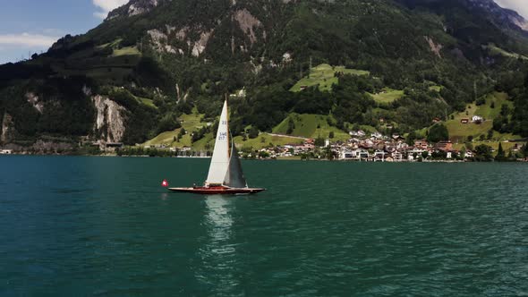 A Sailboat Floats on a Picturesque Lake at the Foot of the Alpine Mountains