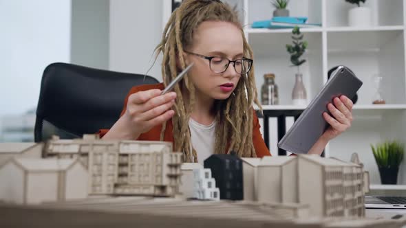 Female Architect with Dreadlocks Working with Wooden Model of New Buildings 