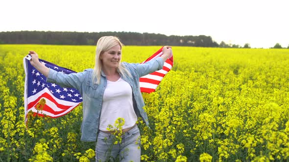 Adult Woman Holding American Flag with Pole Stars and Stripe in a Yellow Rapeseed Field