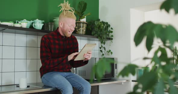 Thoughtful albino african american man with dreadlocks using tablet