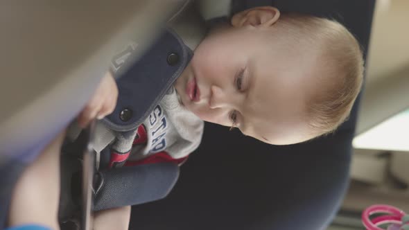 Vertical Video Baby Boy Sitting in Carseat Holding Digital Tablet in Hands Watch
