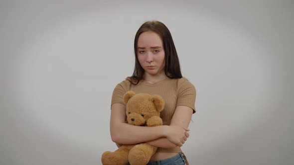 Depressed Frustrated Young Woman Standing with Teddy Bear Looking at Camera with Sad Facial