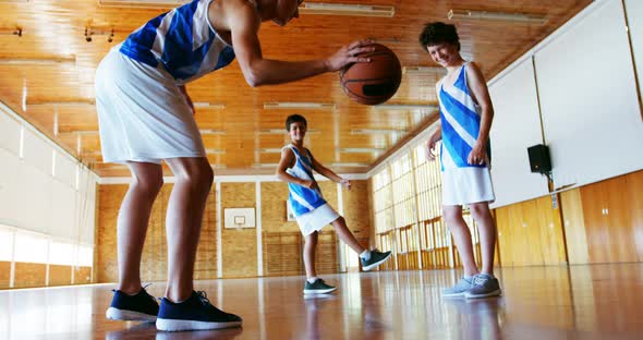 Schoolboys playing basketball in basketball court