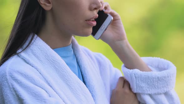 Upset Woman in Bathrobe Talking Phone Outdoors, Bad News, Health Problems