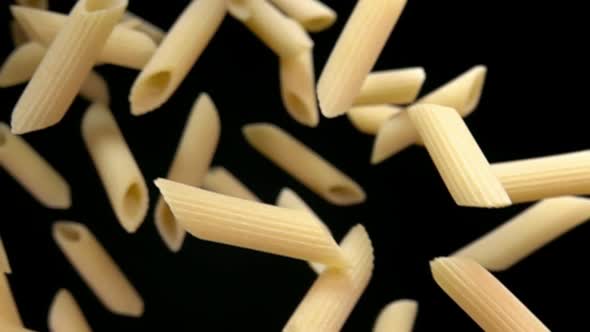 Closeup of the Pasta Penne Falling Down on a Black Background