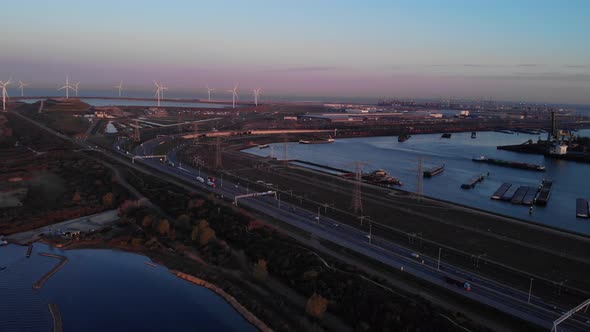 Seaport Of Maasvlakte Along With The Windmills In Rotterdam, Netherlands At Dusk. aerial, pullback