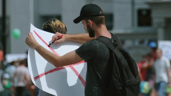 Bearded protest strike activist draws picket banner placard. Riot sign, poster.