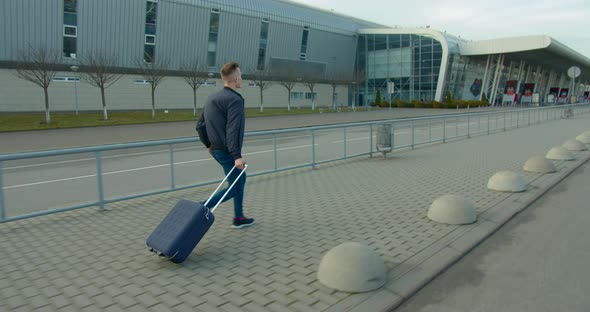 The Guy Is Running To the Airport with a Suitcase. Late for the Plane. Sunny Day.