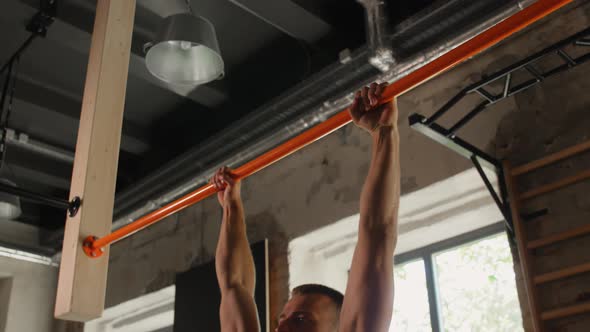 Man Exercising on Bar and Doing Pull-ups in Gym