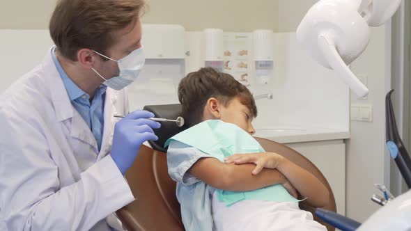 Little Cute Boy Refusing Showing His Teeth To the Dentist, Looking Sad and Scared