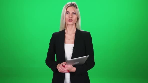 Woman Reporter in Suit Looks Into the Camera and Speaks in Lavalier Microphone Holding a Tablet in