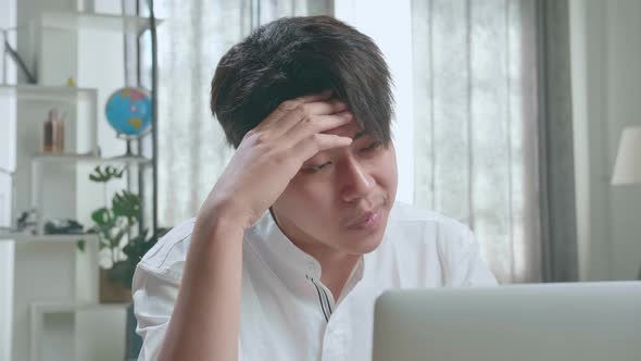 Close Up Of Asian Man Student Being Tired While Using Computer To Study Online At Home