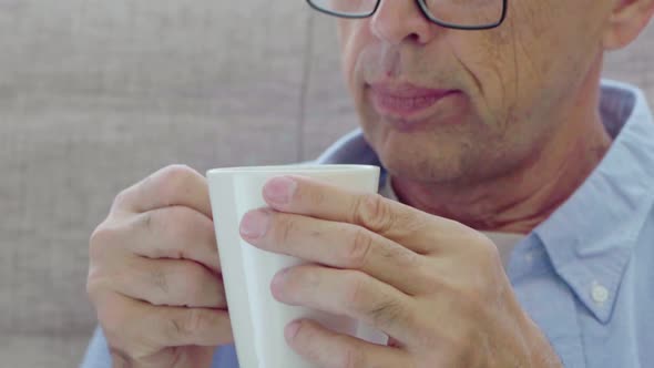 An Elderly Man Drinks From a Mug