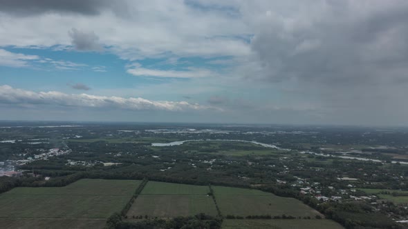 Aerial fly in hyperlapse shot of Cu Chi, Vietnam with greenhouse, farms, forests on sunny day with b