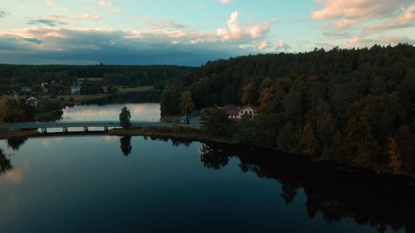 Aerial dolly shot of natural lake surrounded by forest and small village Kowalskie Blota in Poland.