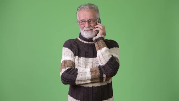 Handsome Senior Bearded Man Wearing Warm Clothing Against Green Background