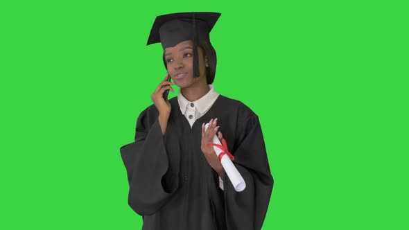 African American Female Student in Graduation Robe Talking on the Phone on a Green Screen, Chroma