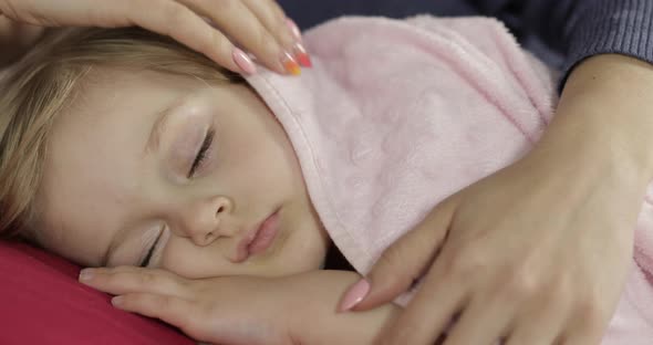 Young Mother Taking Care of Her Little Baby Girl While She Sleep. Girl on Bed