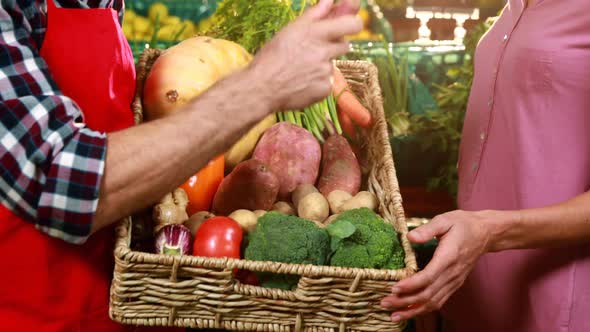 Male staff assisting a woman in shopping vegetables at organic section