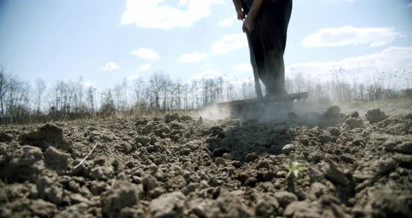 Farmer Works Rake on the Groundt He Soil, Loosens the Ground. Hoeing Field. Slow Motion. Close Up