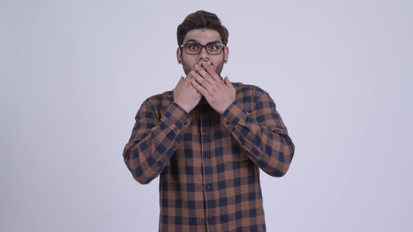 Young Bearded Indian Hipster Man Covering Mouth and Looking Guilty