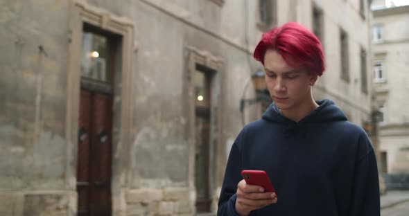 Crop View of Millennial Hipster Guy with Earring Looking and Scrolling Phone Screen. Young Man with