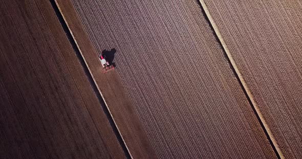 Dark Brown Unseeded Field and Tractor Plowing Land in Spring