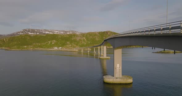 Aerial drone flies along Sommaroya Island Bridge. Seagulls fly past, Northern Norway. Windmills in t