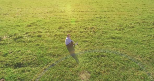 Low Orbital Flight Around Man on Green Grass with Notebook Pad at Yellow Rural Field.