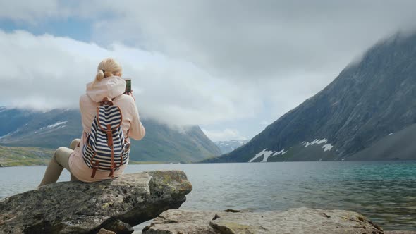 A Woman Takes a Picture of a Scenic View of a High-mountainous Norwegian Lake