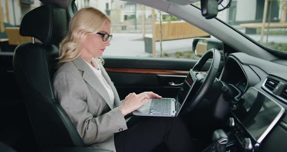 Portrait of Successful Businesswoman Working with Laptop Computer at Luxury Car.