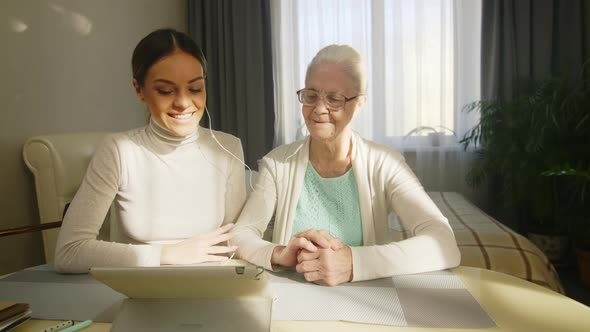 Joyful Senior Woman and Granddaughter Waving at Tablet