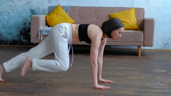 Cute Brunette Woman Does Yoga Exercises at Modern Home at Sofa Background