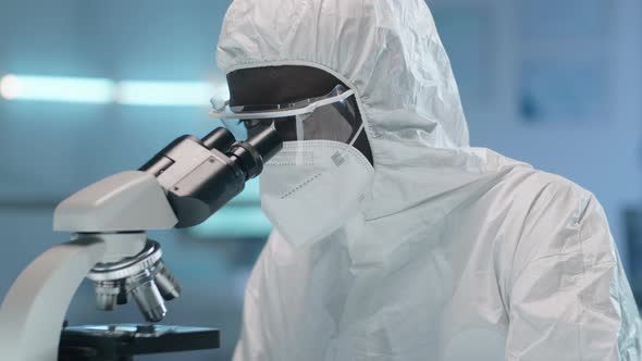 Afro-American Scientist in Protective Suit Using Microscope