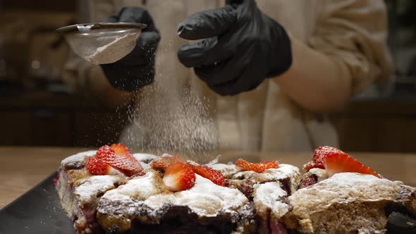 Pastry Cook Sprinkles Strawberry Cakes with Sugar Powder