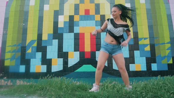 Dancing Female. happy mixed race woman dancing performance with long dreadlocks in shorts