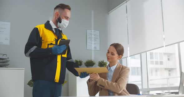 Delivery Man in Face Protective Mask and Gloves Giving Parcel Envelop to Female Customer at Office