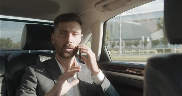 A Confident Businessman is talking on his Phone while traveling in Business Class Car.