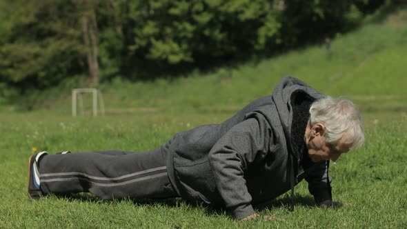 Active Senior Old Man Do Push-ups Physical Exercises in Sport Playground