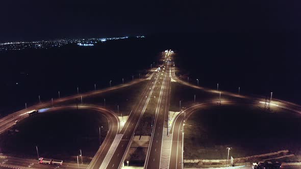 Drone aerial shot of night traffic on a highway showing cars and lanes of light with bridges