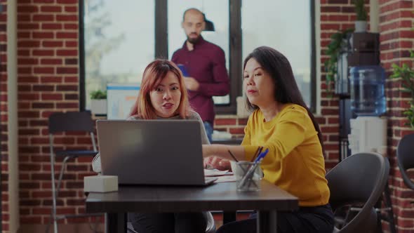 Team of Employees Examining Finance Information on Laptop