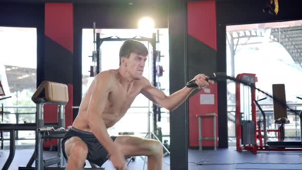 Male exercising with ropes swing at the gym