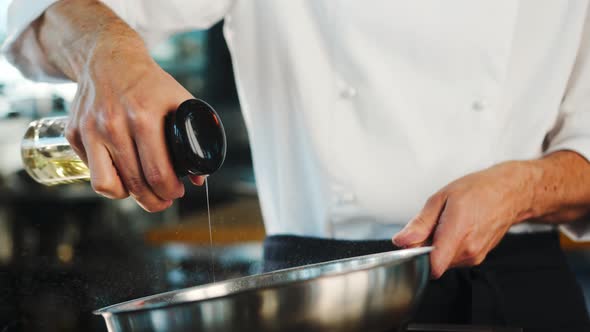 Close-up: Chef pouring oil on a frying pan before cooking