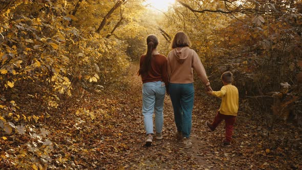 Mom Walks with Her Children in the Autumn Park