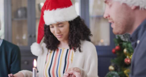 Two diverse female and male friends in santa hats praying at christmas time
