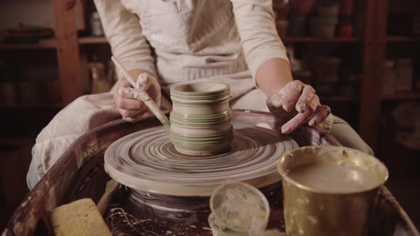 Young Woman Working with a Wet Clay  Painting the Clay in Green Color with a Brush