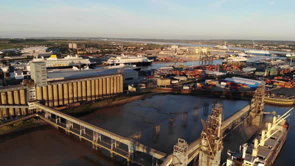 Flying over a boat with cranes, moored in London container terminal at sunset