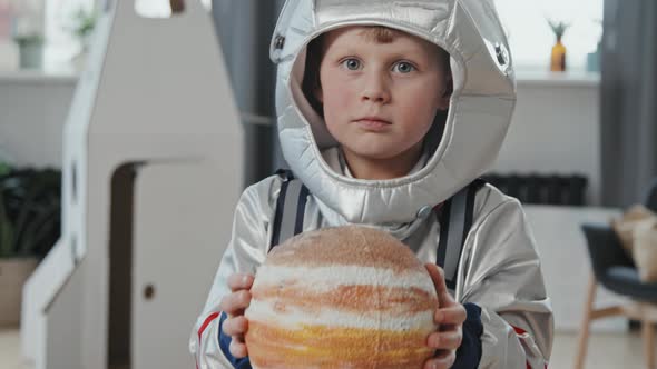 Cute Boy in Spacesuit Holding Model of Planet